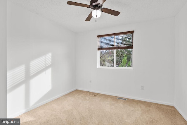 unfurnished room with ceiling fan, baseboards, light colored carpet, and visible vents