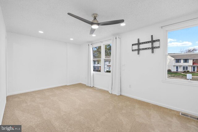 unfurnished room with visible vents, ceiling fan, carpet, and a textured ceiling