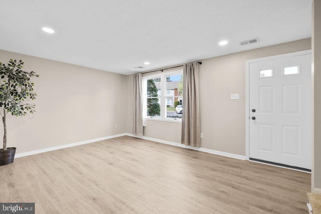foyer featuring baseboards, light wood-style flooring, and visible vents