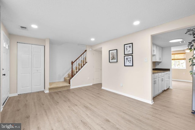unfurnished living room with stairs, recessed lighting, baseboards, light wood finished floors, and visible vents