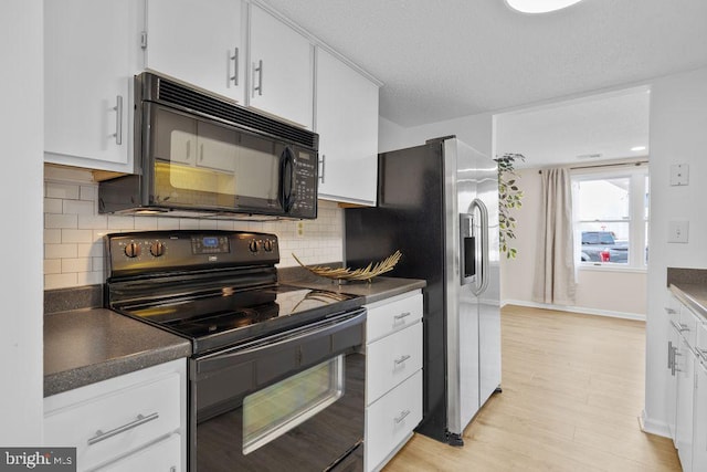 kitchen featuring light wood finished floors, dark countertops, white cabinetry, black appliances, and backsplash