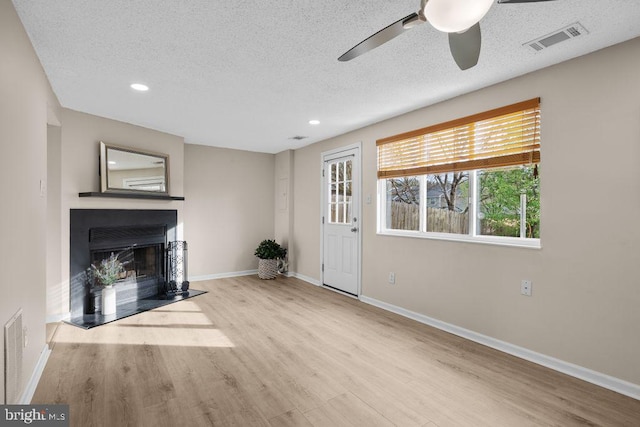unfurnished living room featuring visible vents, a ceiling fan, wood finished floors, and a fireplace