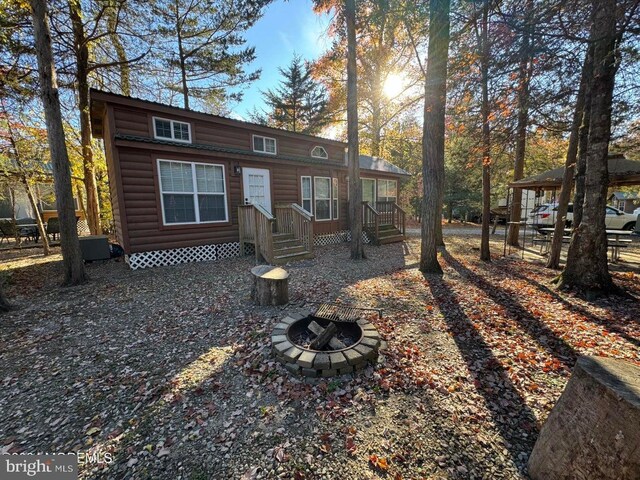 724 Monmouth Rd Unit 26, Cream Ridge, NJ 08514 - rear view of property with log veneer siding and an outdoor fire pit