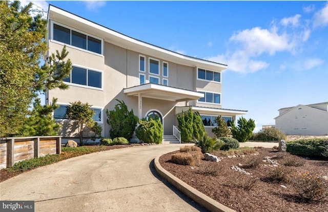 view of front of house featuring stucco siding, driveway, and fence