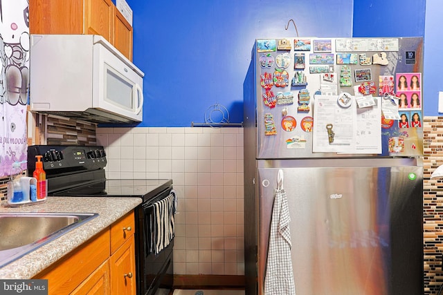 3903 N Marshall St, Philadelphia, PA 19140 - kitchen with white microwave, light countertops, freestanding refrigerator, black electric range, and brown cabinetry