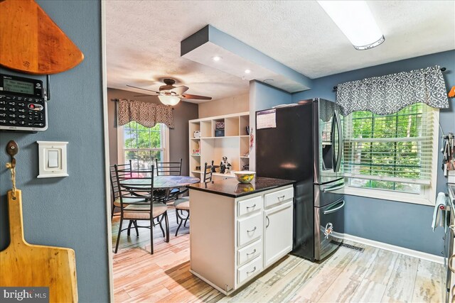 kitchen featuring stainless steel refrigerator with ice dispenser, a ceiling fan, white cabinetry, and a textured ceiling