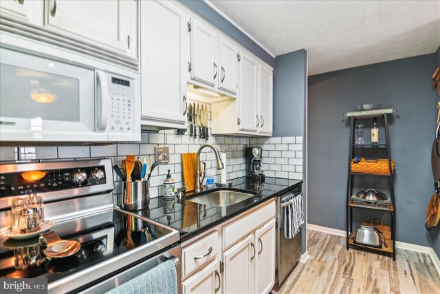 kitchen with white cabinets, backsplash, appliances with stainless steel finishes, and a sink