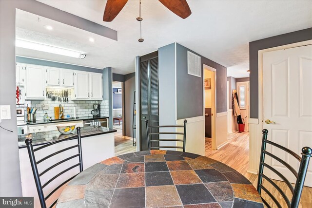 kitchen with ceiling fan, dark countertops, tasteful backsplash, a sink, and white cabinets