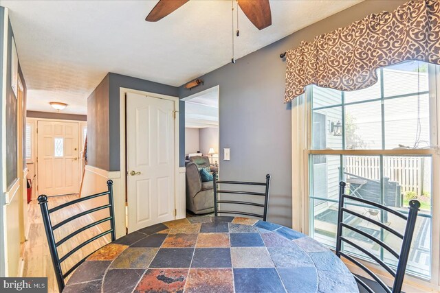 dining space featuring ceiling fan and stone finish flooring