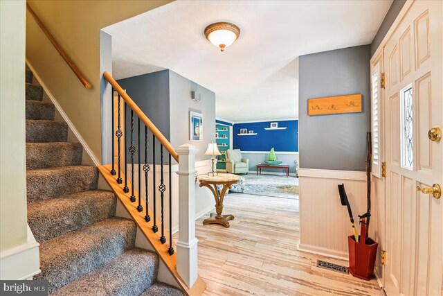 entryway featuring visible vents, wood finished floors, stairway, and a wainscoted wall