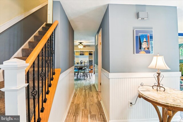 hallway featuring stairway, wainscoting, and wood finished floors