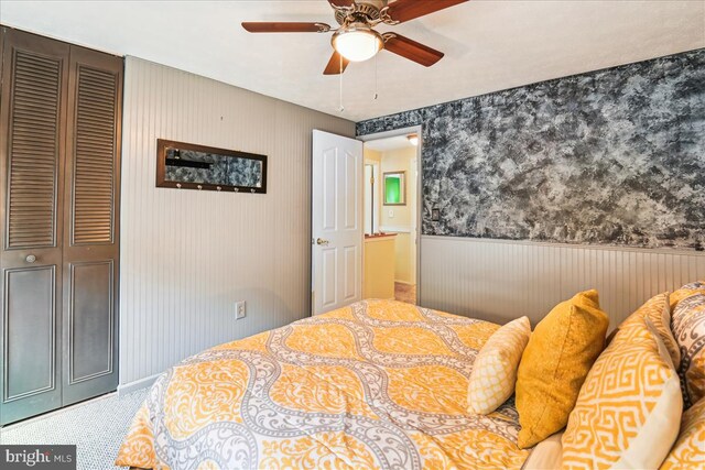bedroom with ceiling fan and wainscoting