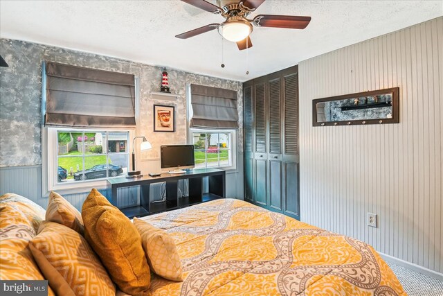 bedroom featuring a ceiling fan, a closet, wallpapered walls, and a textured ceiling