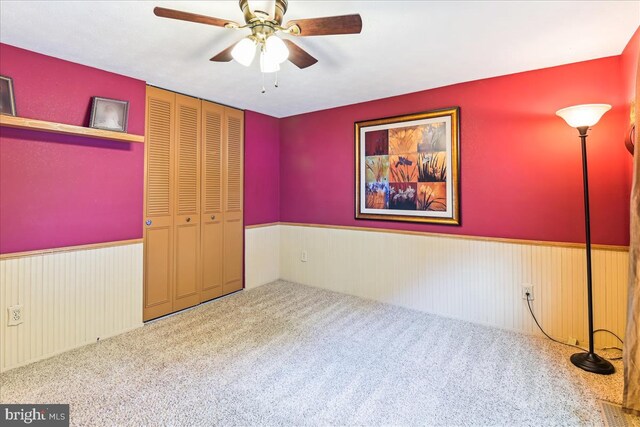 unfurnished bedroom featuring a closet, carpet floors, wainscoting, and visible vents