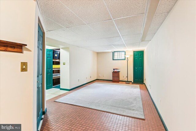 below grade area featuring tile patterned floors, baseboards, and a paneled ceiling
