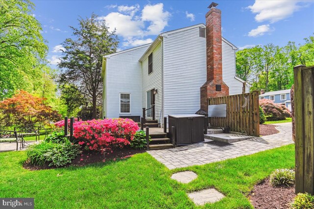 back of house with a yard, a patio, and a chimney
