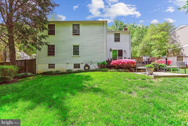 rear view of property featuring a lawn, fence, a chimney, and a patio