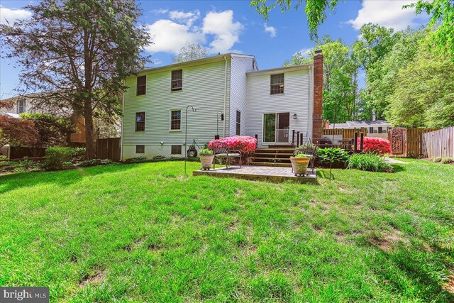 rear view of house featuring a patio area, fence, a yard, and a chimney