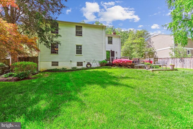 back of house with a lawn, fence, and a chimney