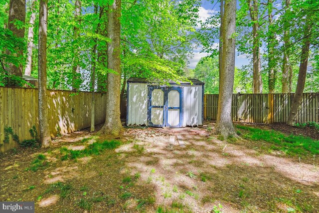 view of yard featuring an outbuilding, a fenced backyard, and a storage unit