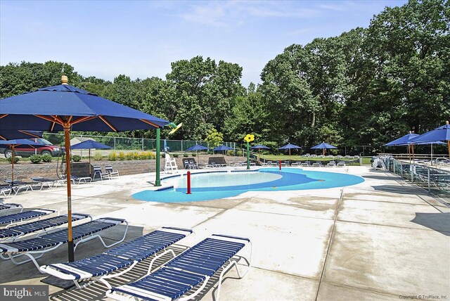 community pool with a patio area and fence