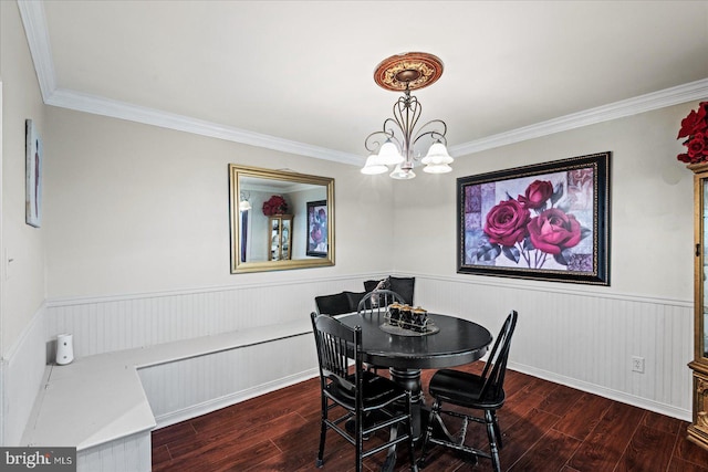 dining space with a chandelier, hardwood / wood-style floors, crown molding, and a wainscoted wall