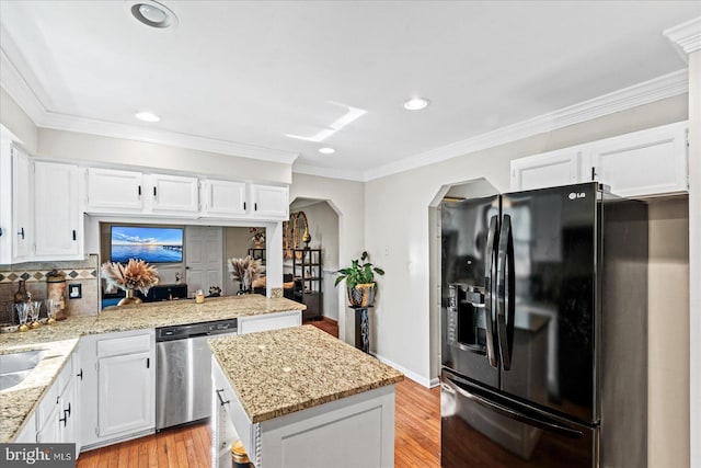 kitchen with arched walkways, black fridge, dishwasher, light wood-style floors, and white cabinetry