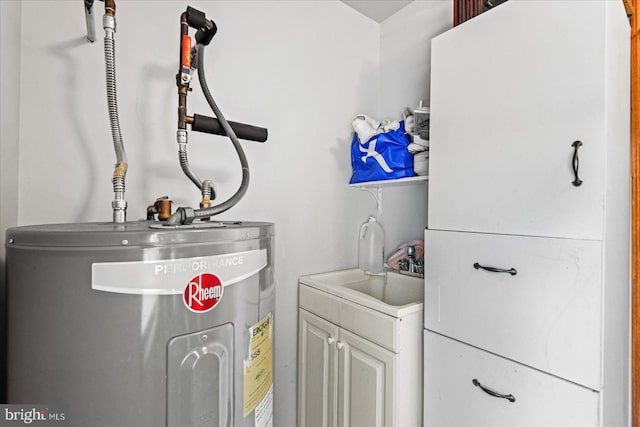 clothes washing area with a sink, cabinet space, and water heater