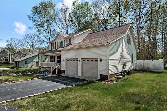 view of front facade featuring aphalt driveway, a shingled roof, an attached garage, and a front yard