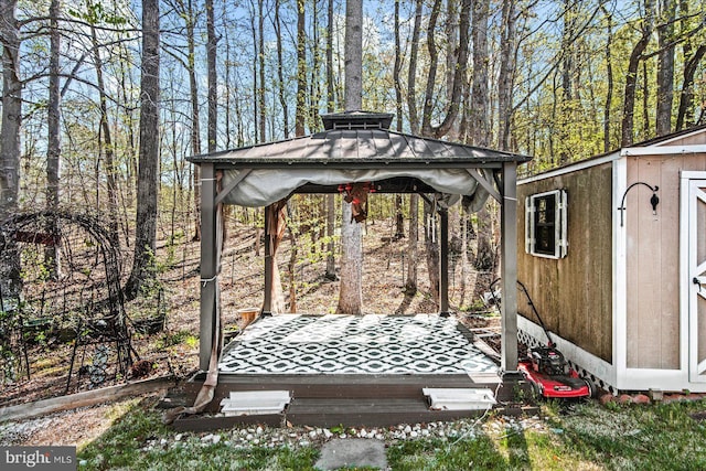 wooden terrace featuring an outbuilding, a gazebo, and a storage unit