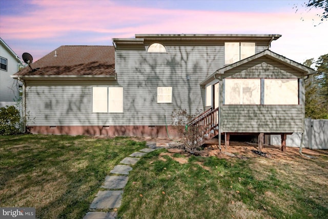 rear view of house with crawl space and a lawn