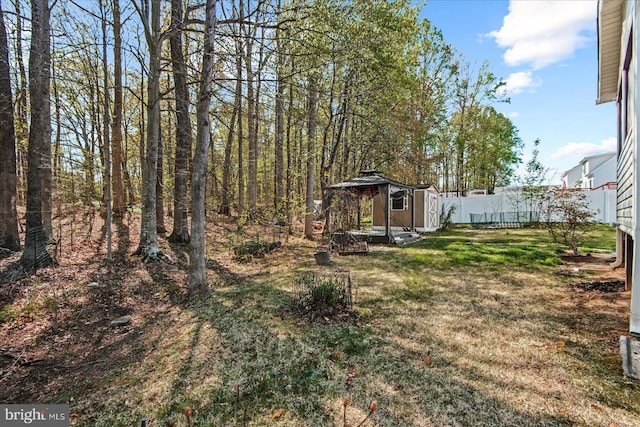 view of yard featuring a storage shed, fence, and an outbuilding