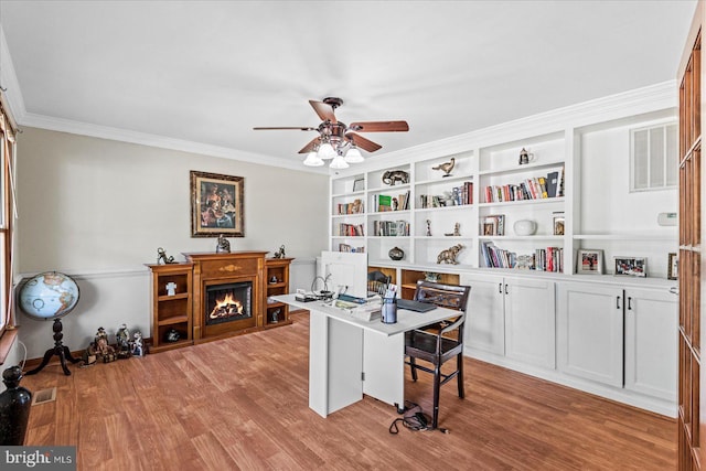 home office featuring light wood-style floors, ceiling fan, ornamental molding, and visible vents