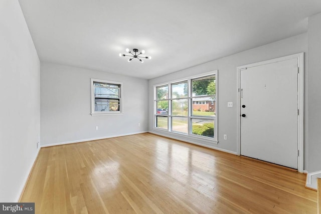 entrance foyer featuring a notable chandelier, baseboards, a healthy amount of sunlight, and light wood finished floors