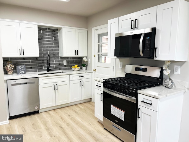 kitchen with white cabinetry, a sink, stainless steel appliances, and light wood finished floors