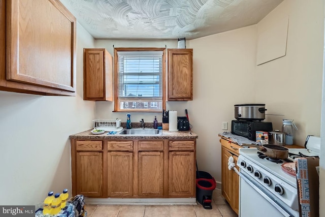kitchen featuring a sink, white range with gas cooktop, light tile patterned flooring, and brown cabinets