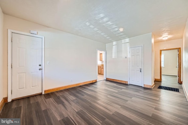 spare room with baseboards and wood finished floors