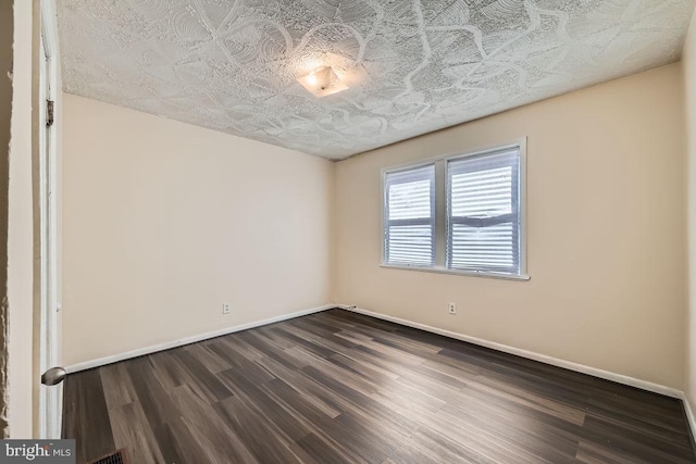 unfurnished room featuring baseboards and dark wood-style flooring