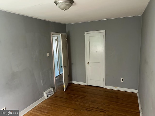 spare room featuring baseboards, visible vents, and wood finished floors
