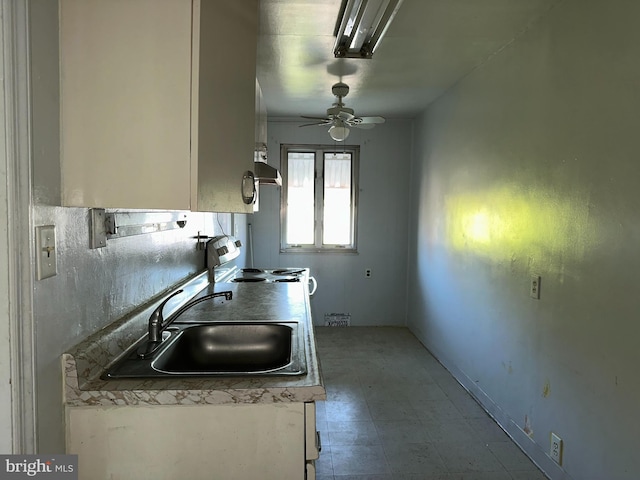 kitchen featuring ceiling fan, electric stove, white cabinetry, under cabinet range hood, and a sink