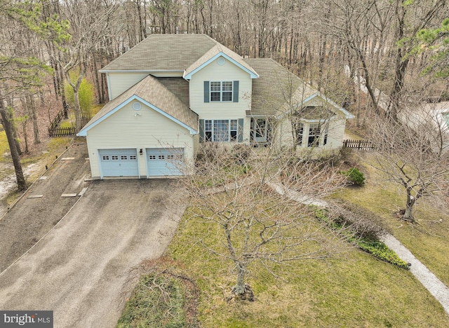 view of front of property featuring a garage, driveway, fence, and a shingled roof