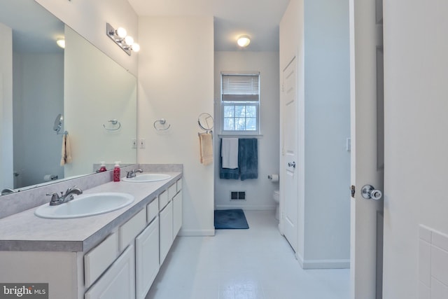 bathroom featuring toilet, double vanity, a sink, and visible vents