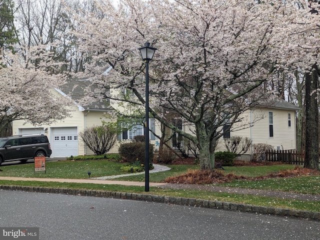 obstructed view of property featuring a garage, fence, and a front lawn
