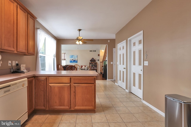 kitchen featuring white dishwasher, brown cabinets, light countertops, and a peninsula