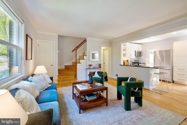 living room featuring stairs, crown molding, visible vents, and light wood-style flooring