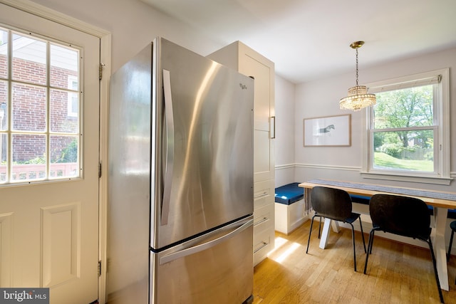 kitchen featuring freestanding refrigerator, light wood finished floors, a chandelier, and pendant lighting