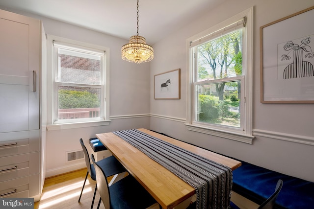 dining space with an inviting chandelier, baseboards, a wealth of natural light, and light wood-type flooring
