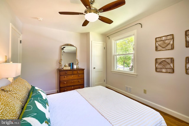 bedroom with a ceiling fan, baseboards, visible vents, and wood finished floors
