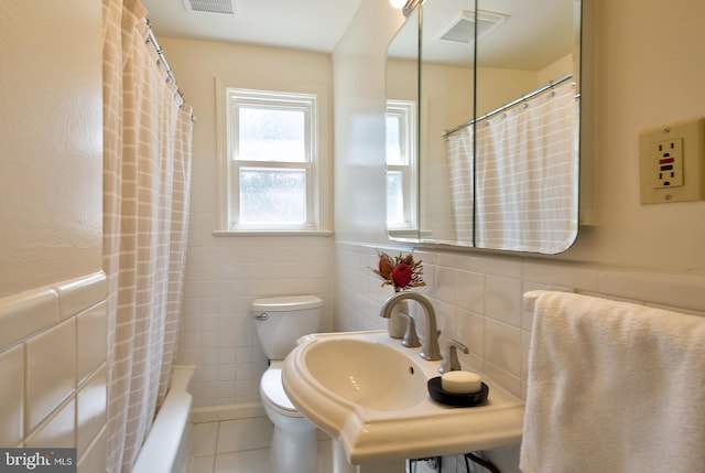 bathroom with visible vents, tile patterned flooring, toilet, tile walls, and a sink