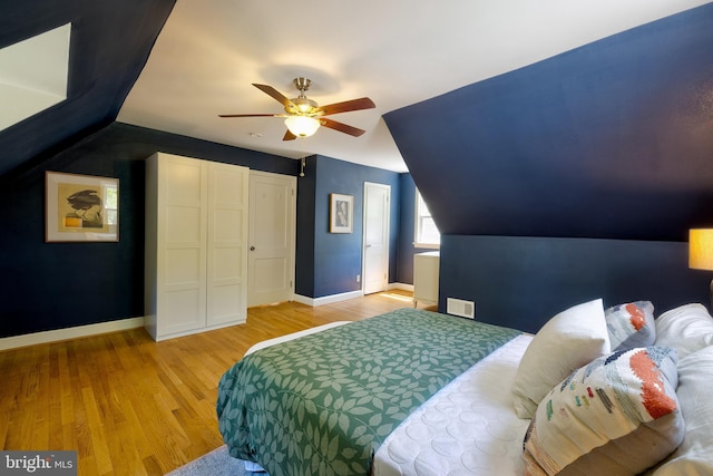 bedroom featuring ceiling fan, visible vents, wood finished floors, baseboards, and lofted ceiling